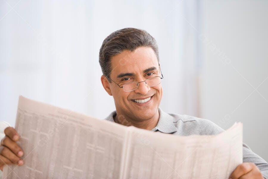 Homem lendo jornal em casa sorrindo