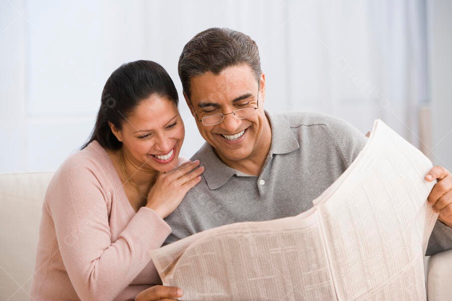 Casal maduro lendo jornal sorrindo