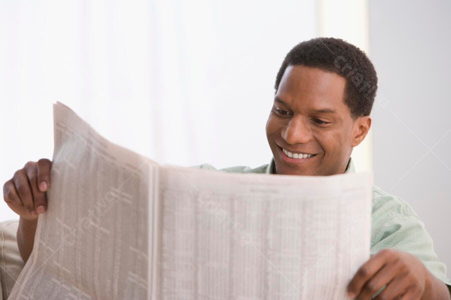 Homem lendo jornal em casa sorrindo