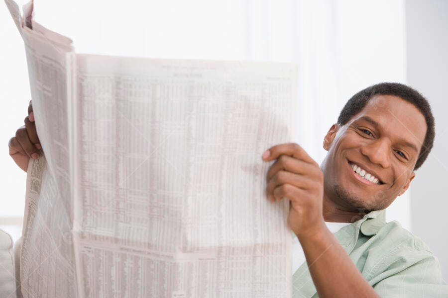 Homem negro lendo jornal sorrindo