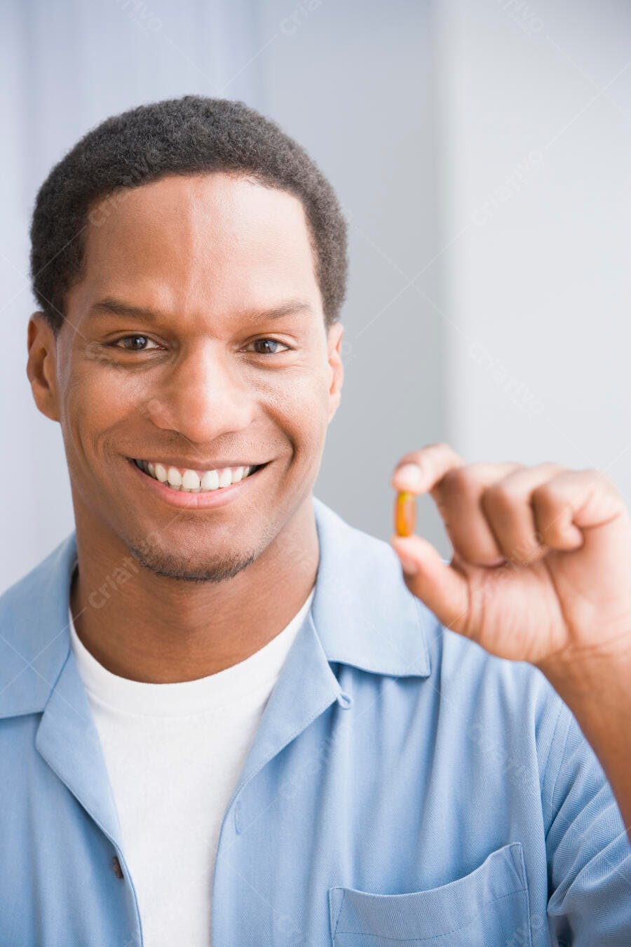 Homem negro sorrindo segurando comprimido