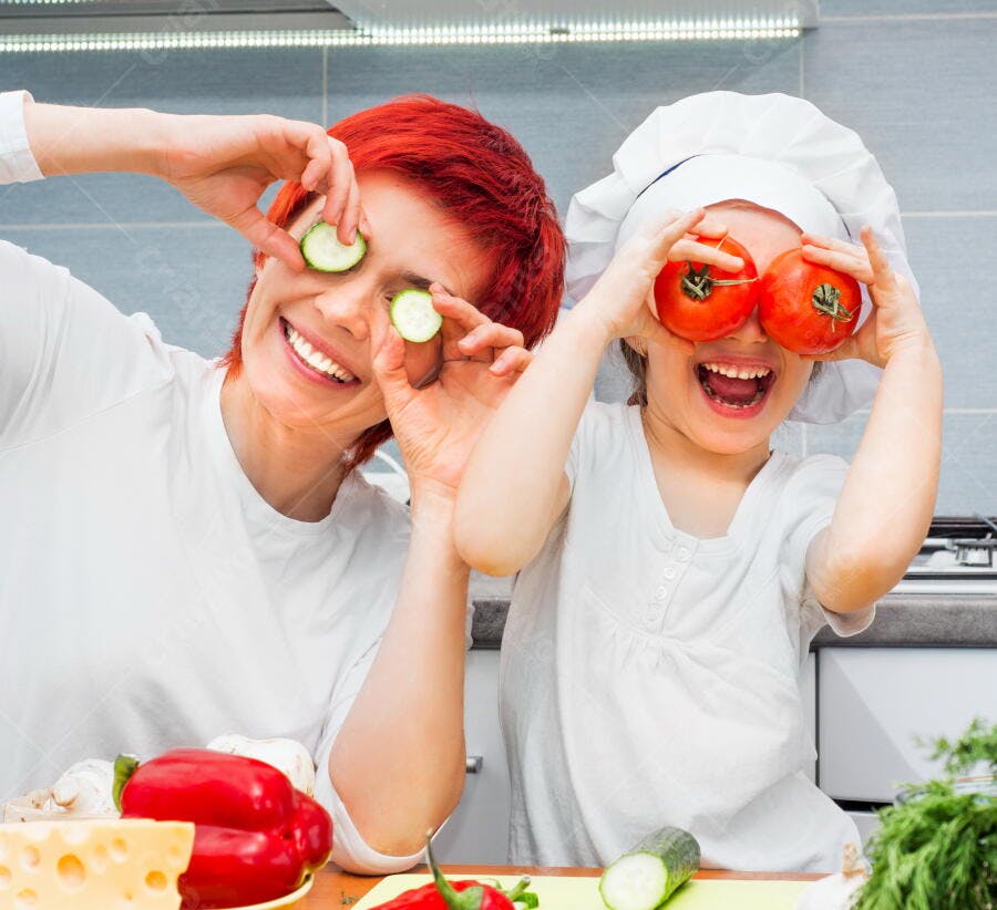 Mãe e filha brincando com legumes na cozinha
