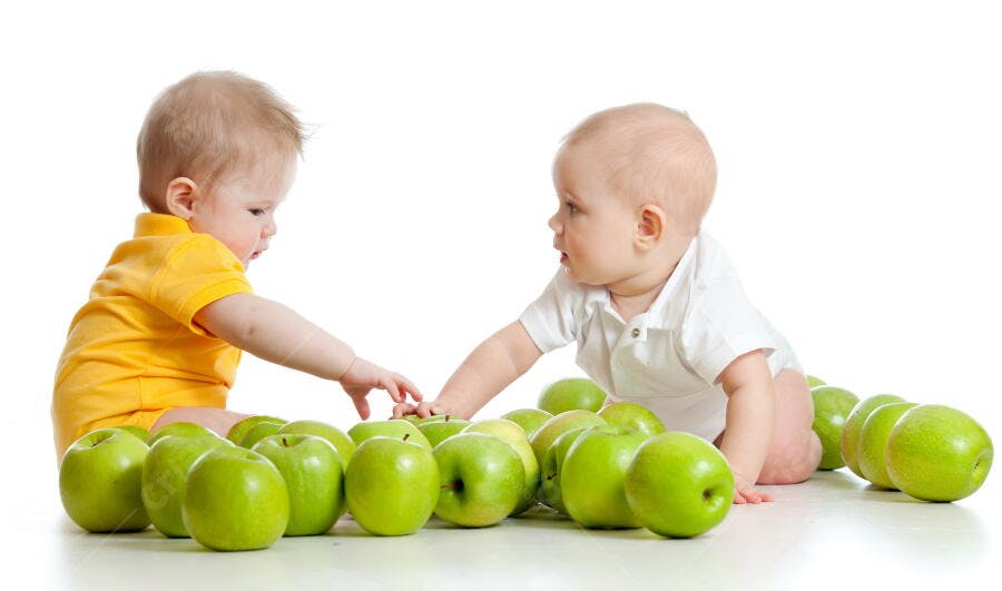 Bebês brincando com maçãs verdes
