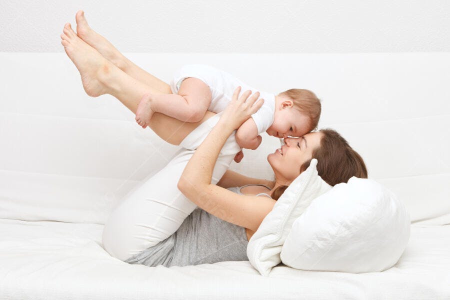 Mãe e bebê brincando na cama
