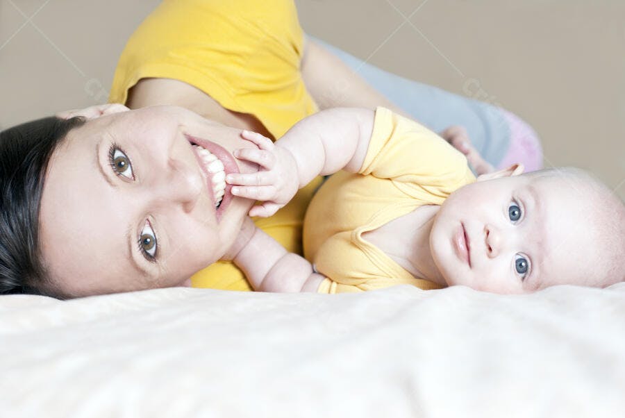 Mãe e bebê sorrindo cama amarela