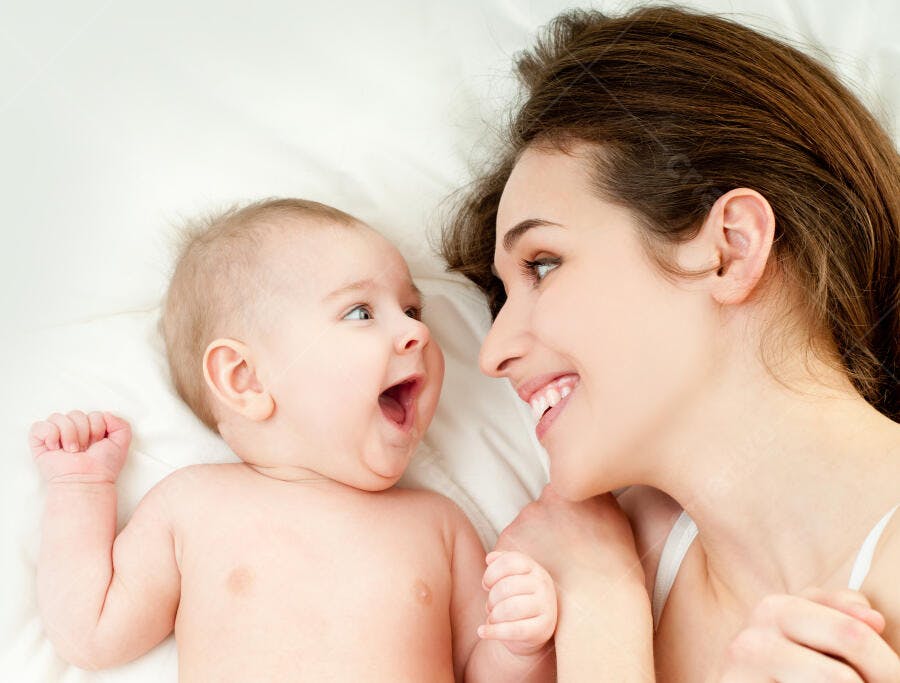 Mãe e bebê sorrindo na cama