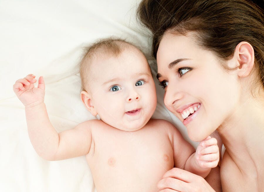 Bebê e mãe sorrindo na cama