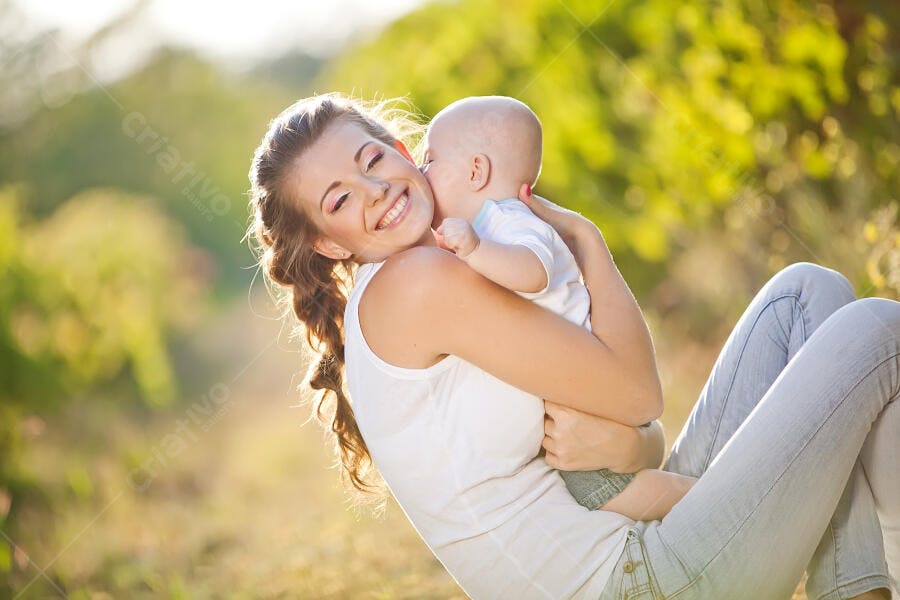 Mãe e bebê sorrindo em parque ensolarado
