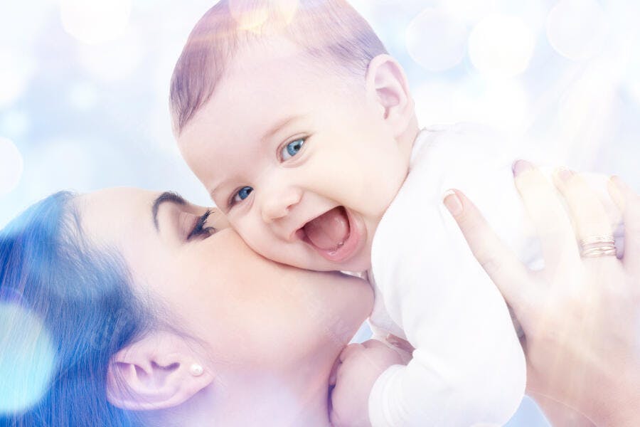 Mãe beijando bebê sorrindo fundo claro