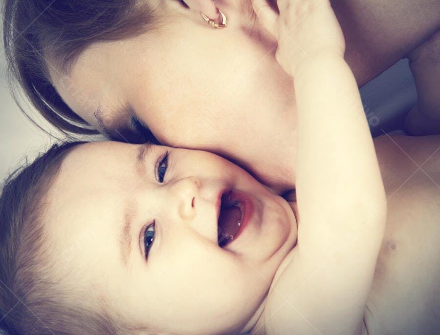 Bebê feliz sendo beijado pela mãe
