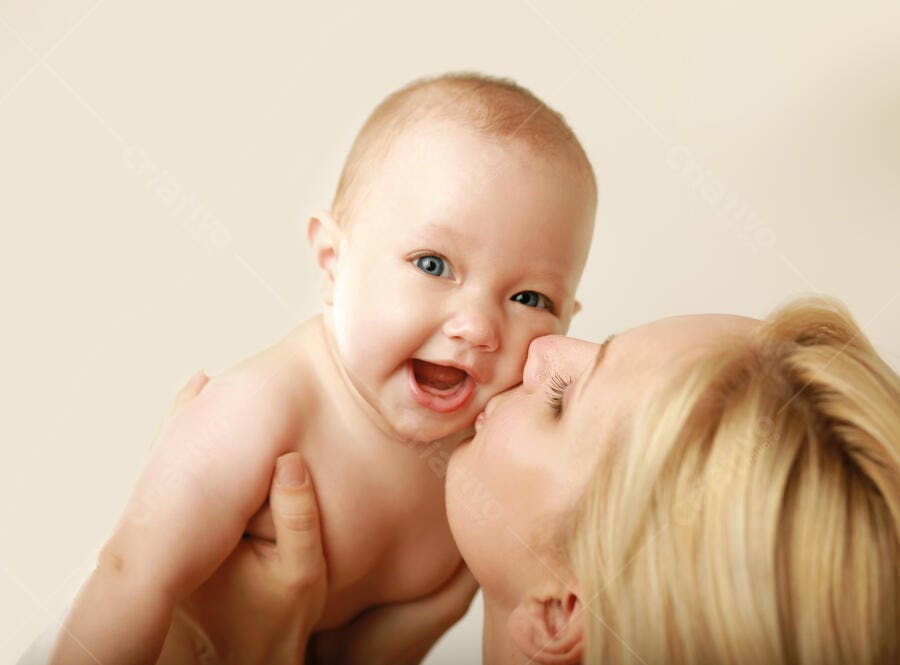 Bebê sorrindo recebendo beijo da mãe