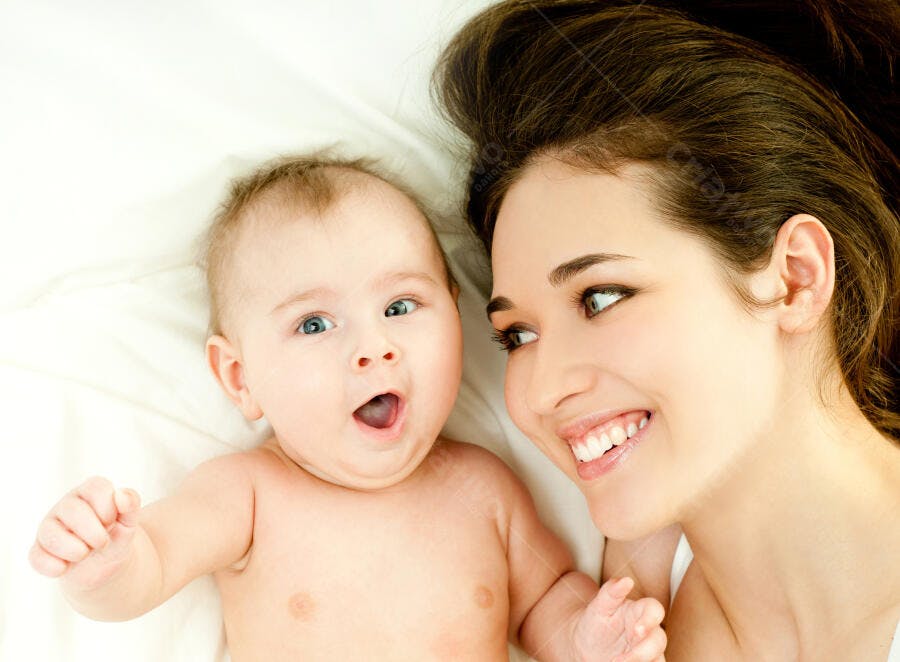 Bebê e mãe sorrindo na cama