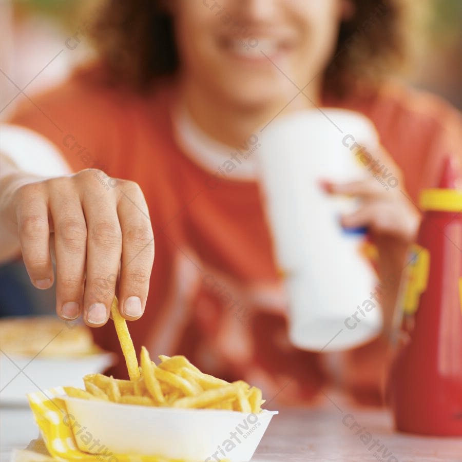 Mão pegando batata frita em lanchonete