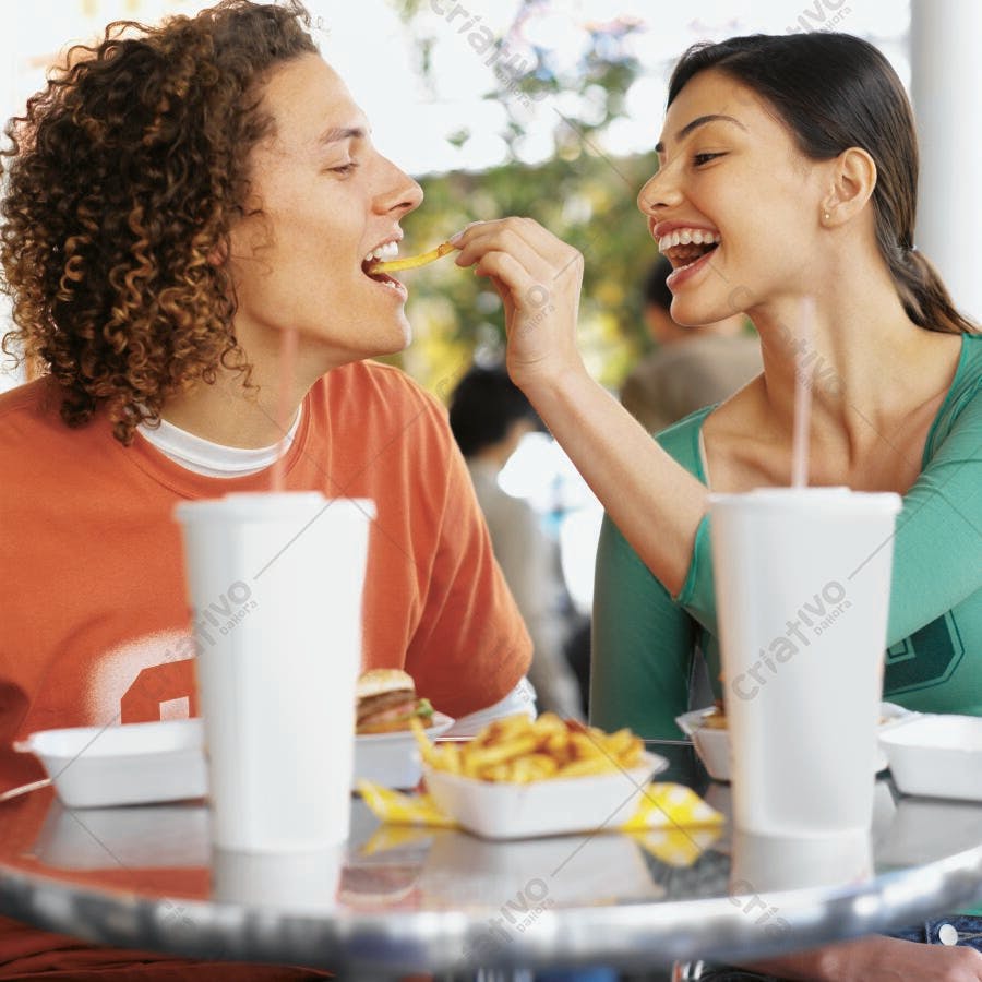 Casal jovem compartilhando batatas fritas em lanchonete