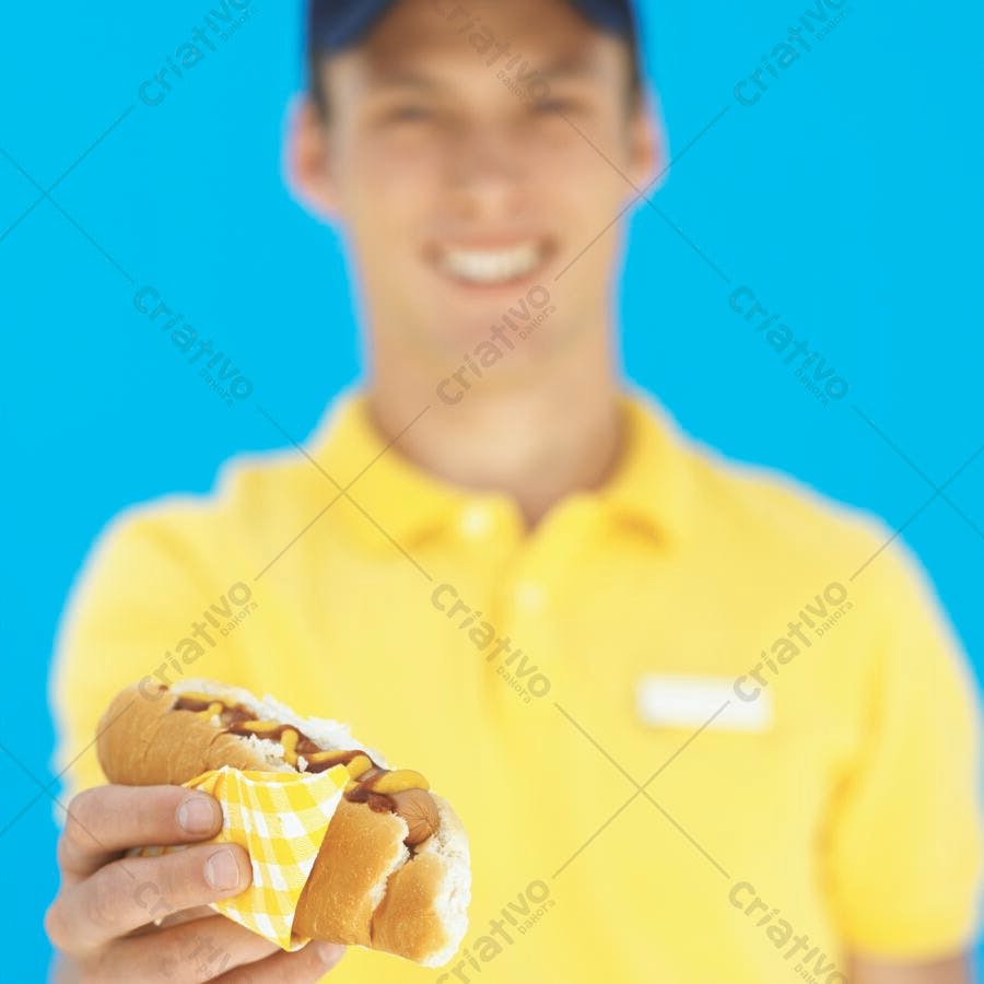 Hot dog com mostarda na mão de um homem