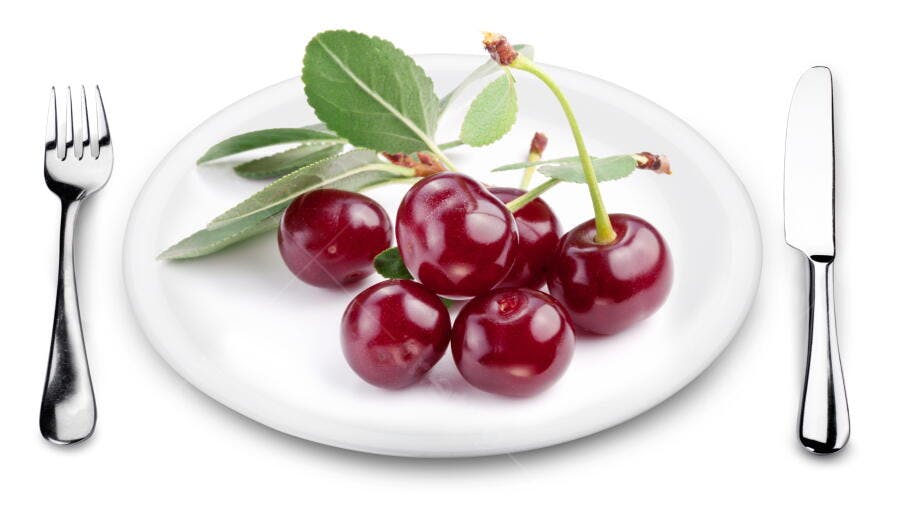Cerejas frescas em prato branco com talheres