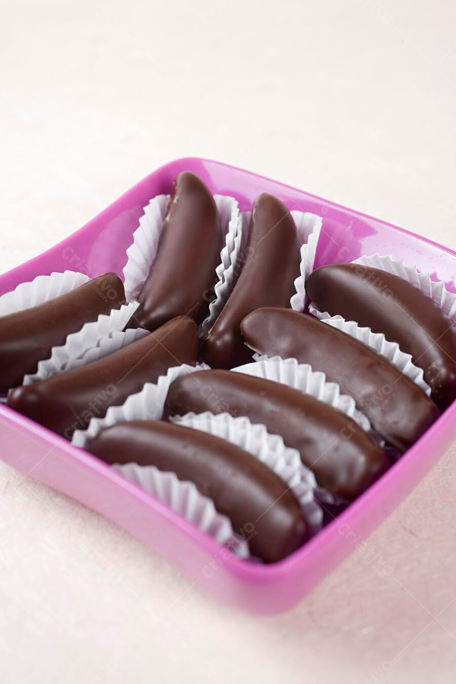Bananas cobertas com chocolate em recipiente rosa