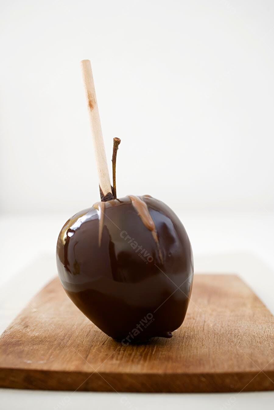 Maçã coberta de chocolate em tábua de madeira