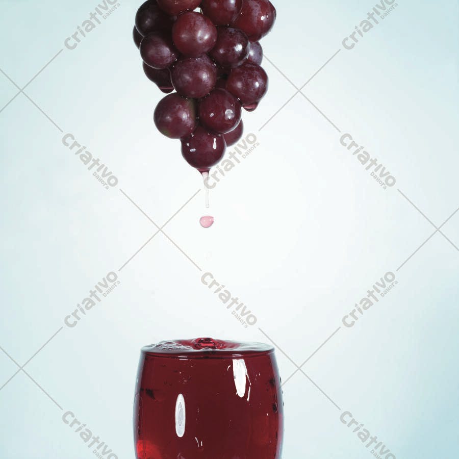 Uvas vermelhas caindo em taça de suco