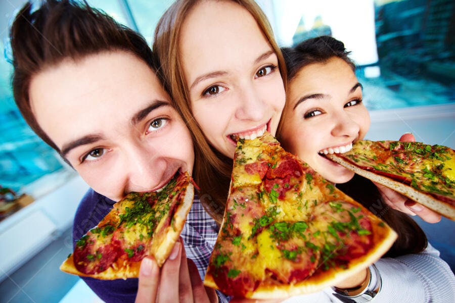 Amigos mordendo fatias de pizza saborosa