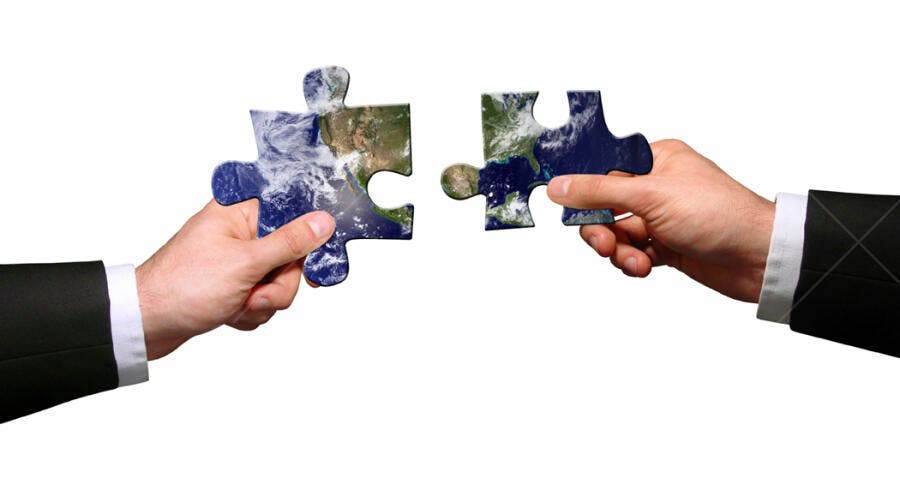 Mãos unindo peças de quebra-cabeça com mapa mundi
