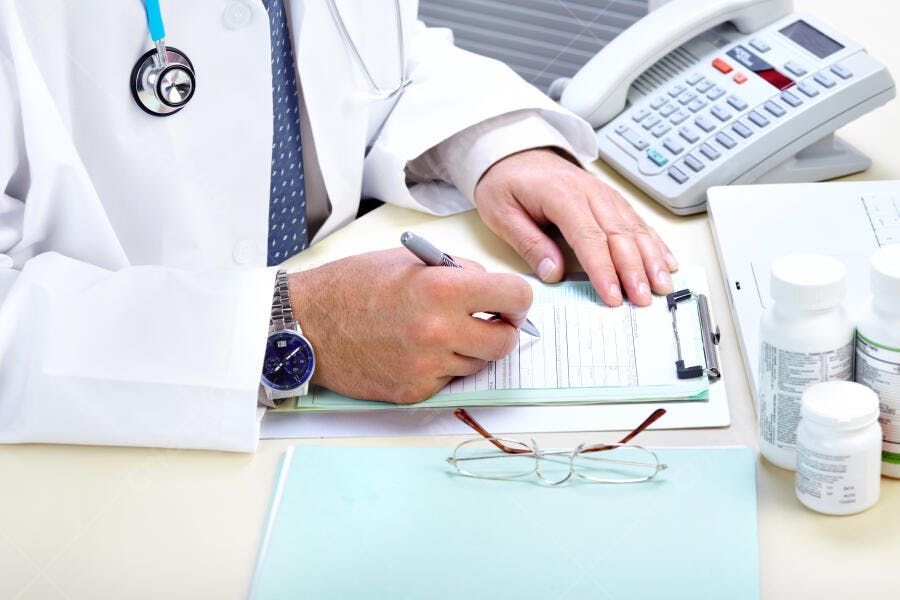 Médico escrevendo receita em consultório