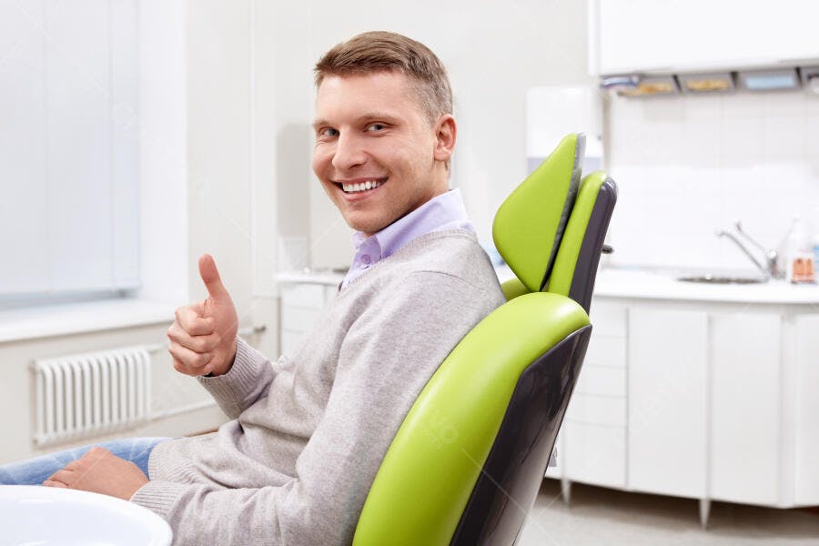 Homem sorrindo na cadeira odontologica