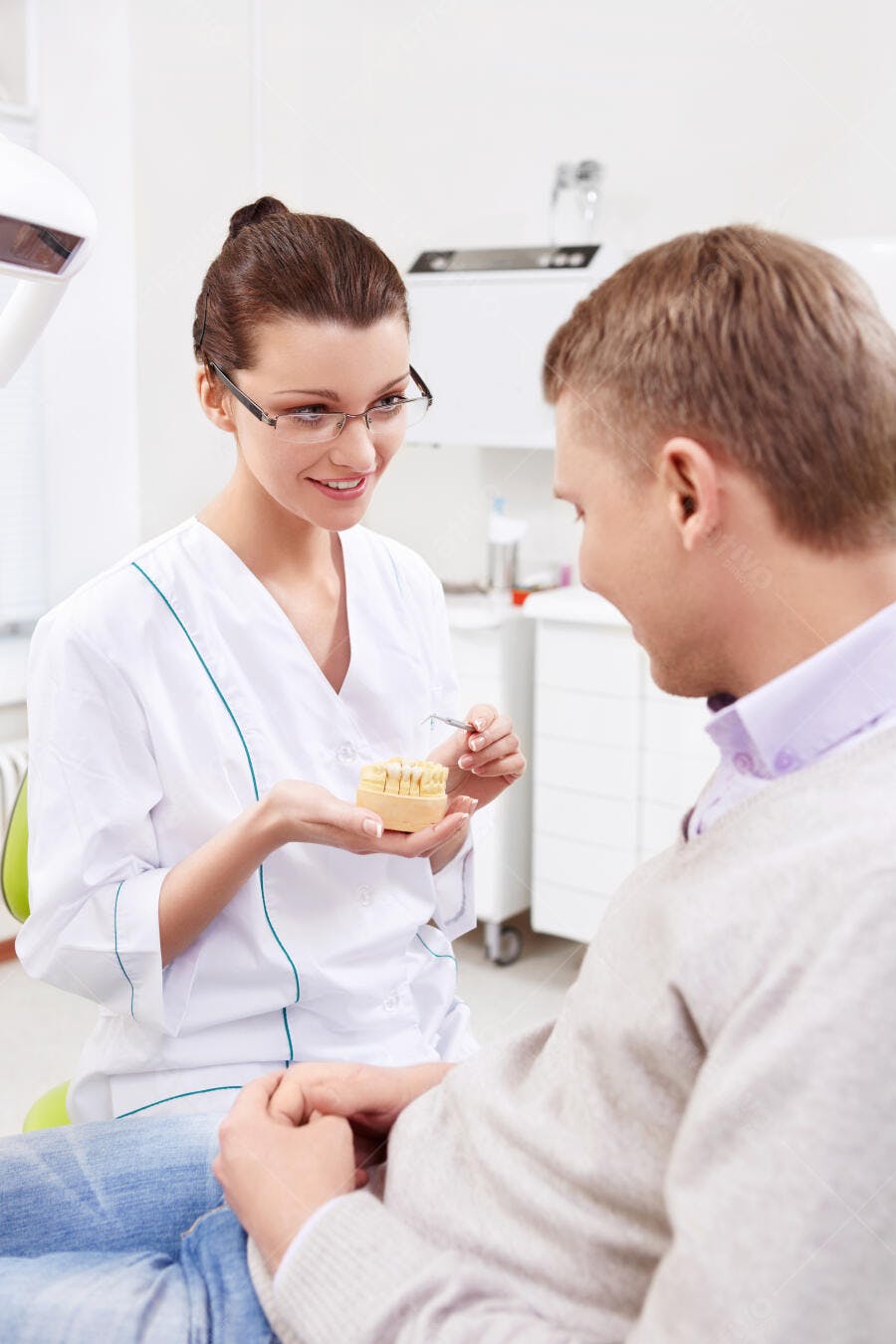 Dentista explicando modelo de dentes a paciente