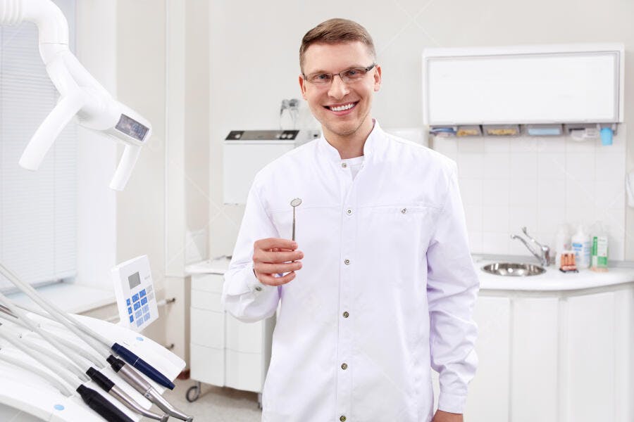 Dentista sorridente segurando espelho odontológico