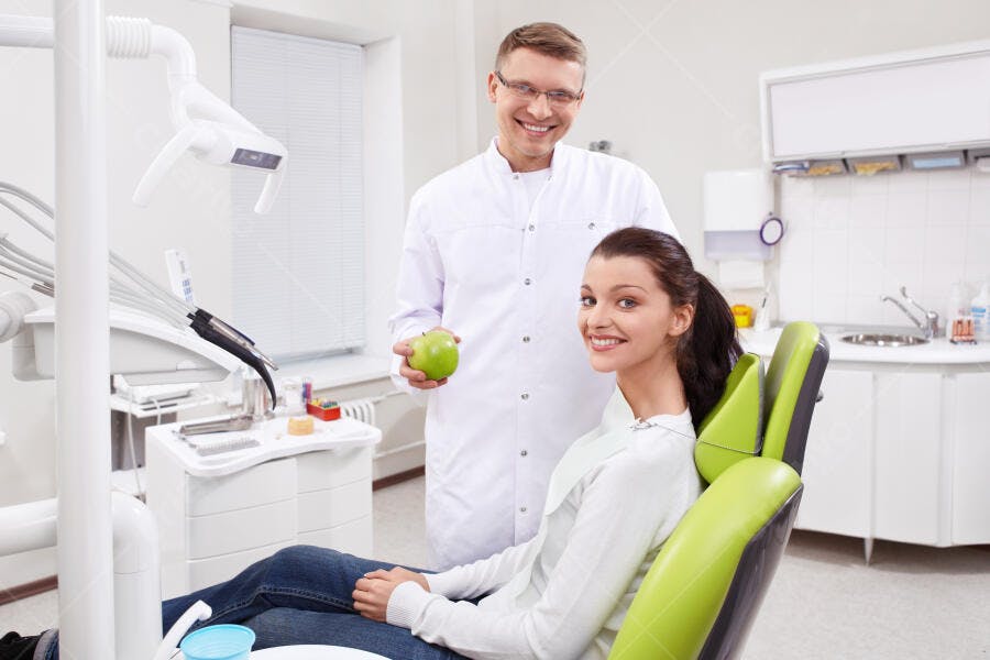 Dentista e paciente com maçã verde consultório