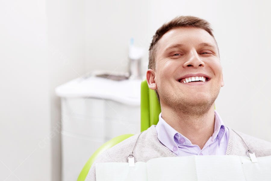 Homem sorrindo no consultório odontológico