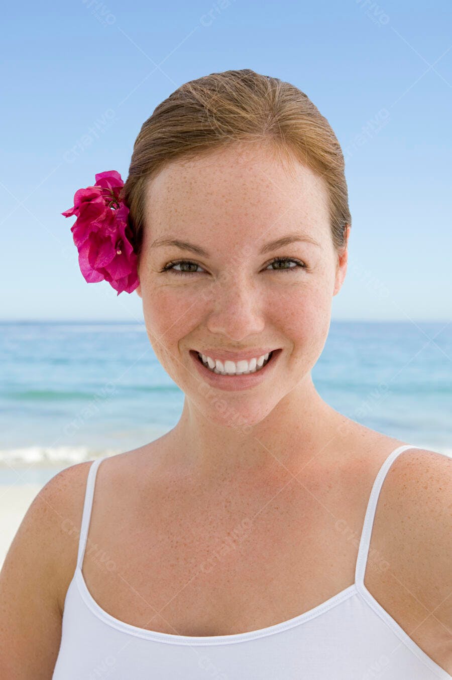Mulher feliz na praia com flor no cabelo