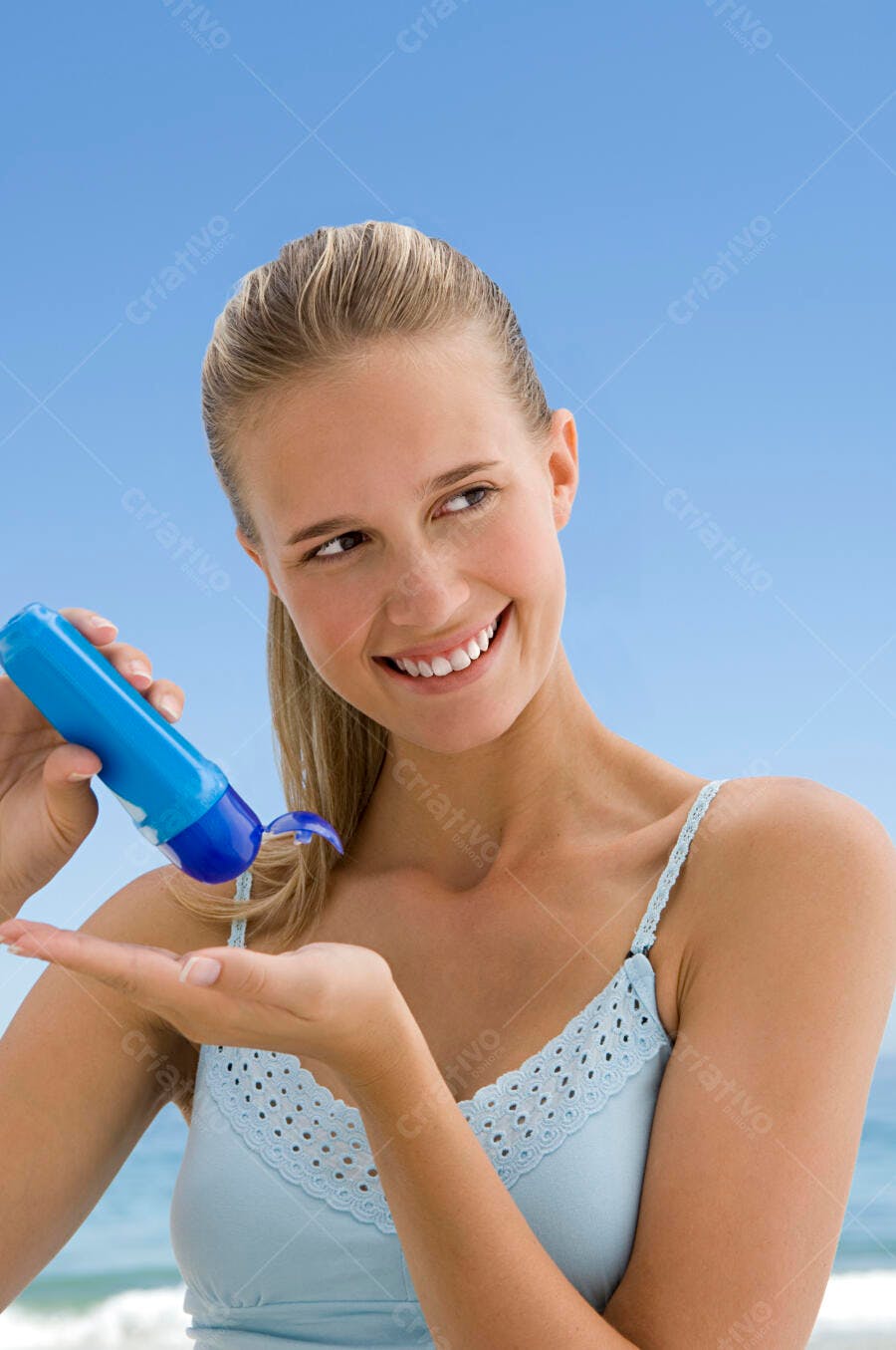 Mulher aplicando protetor solar na praia