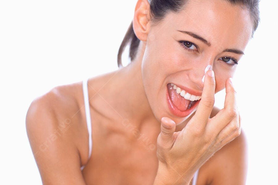 Mulher aplicando creme facial sorrindo