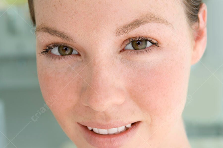Rosto de mulher jovem com sardas e olhos verdes