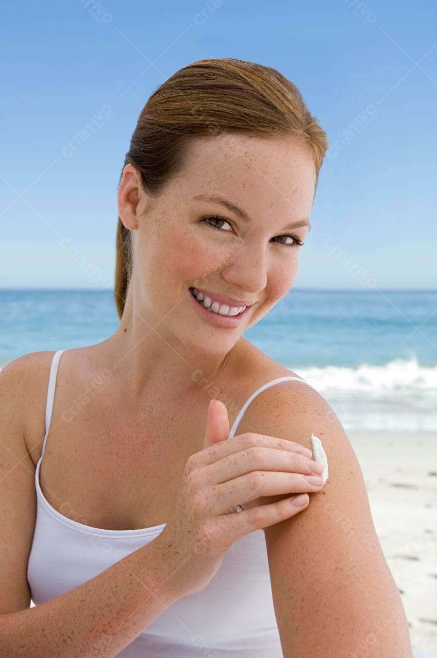 Mulher aplicando protetor solar na praia