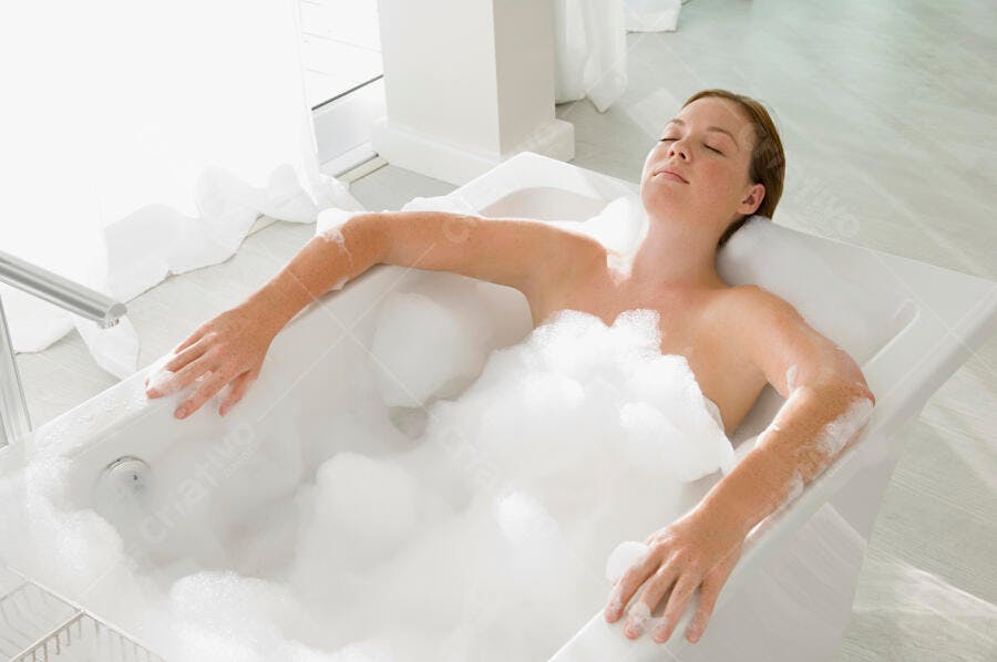 Mulher relaxando em banho de espuma branco