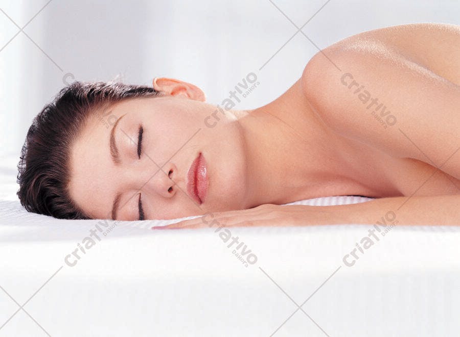 Mulher dormindo serenamente em cama branca