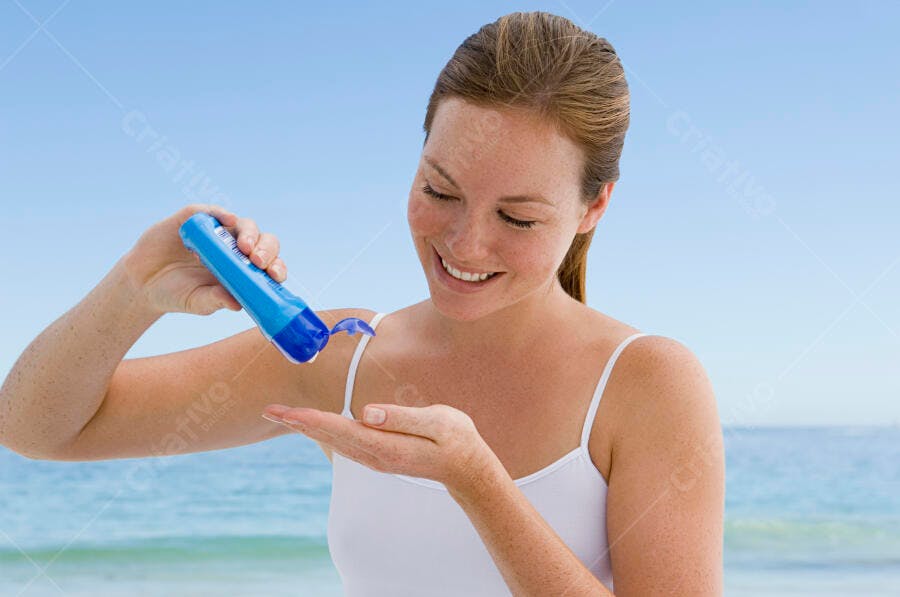Mulher aplicando protetor solar na praia