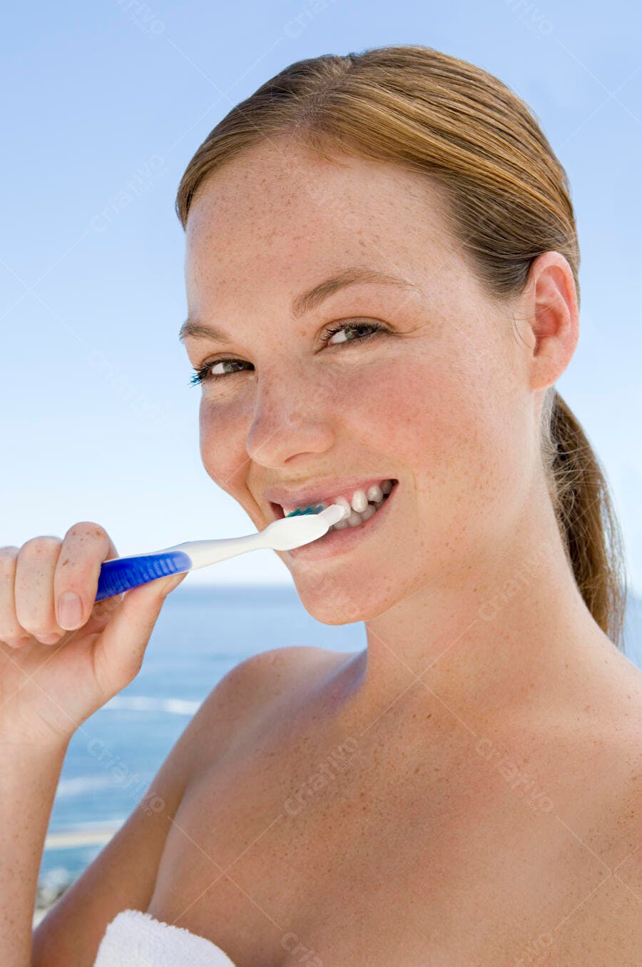 Mulher escovando os dentes perto do mar