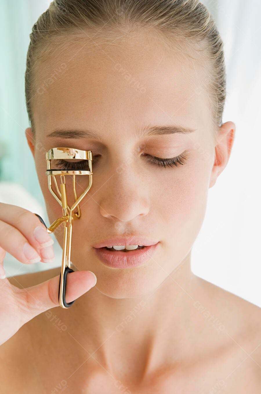 Mulher usando curvex dourado para cílios