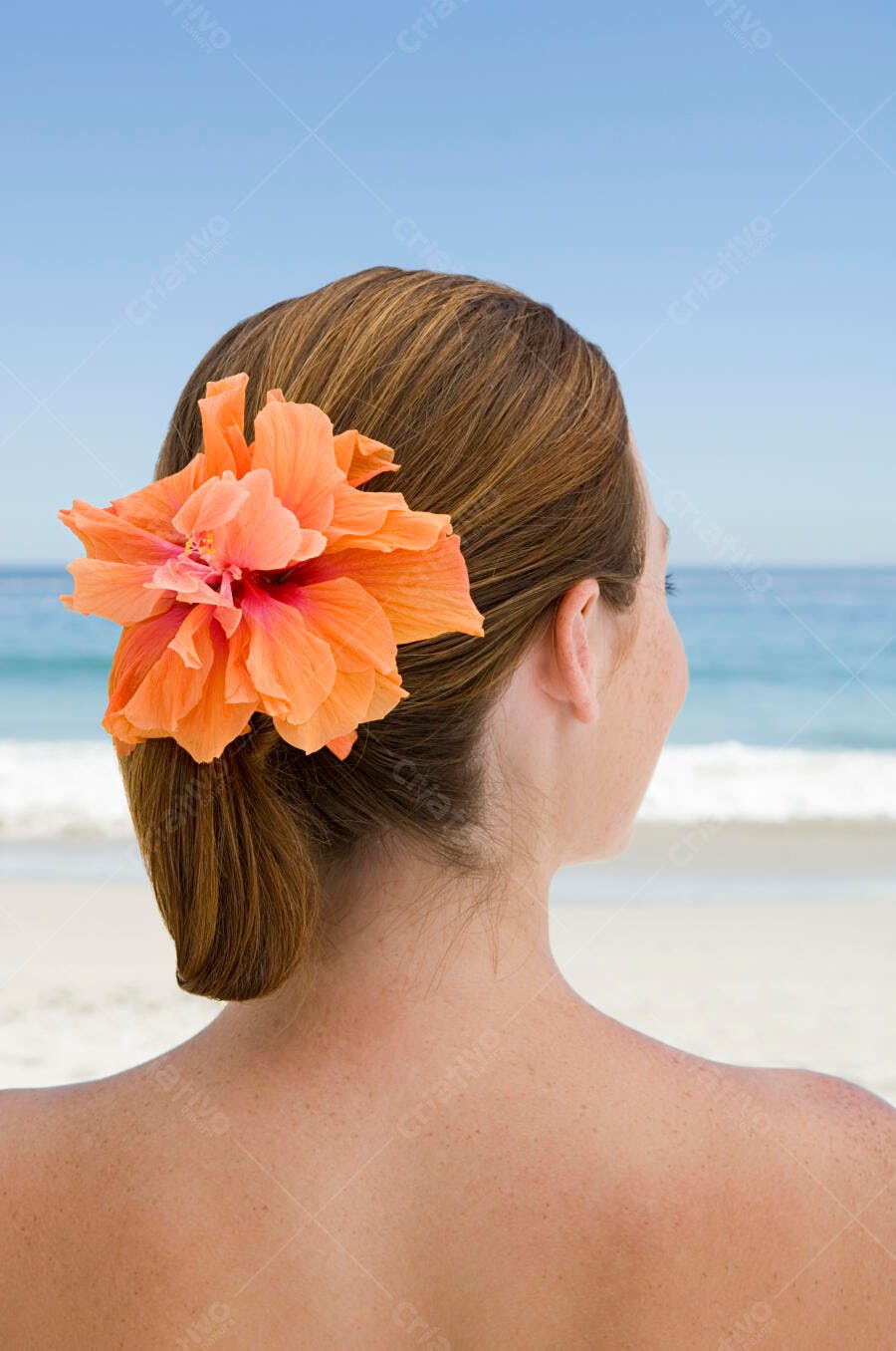 Mulher com flor de hibisco na praia