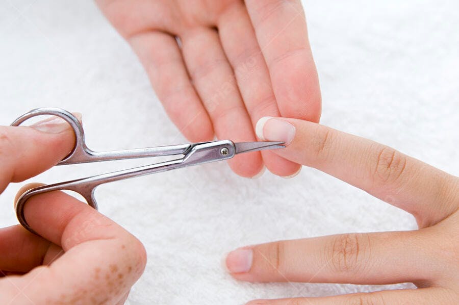 Manicure com tesoura cortando cutícula