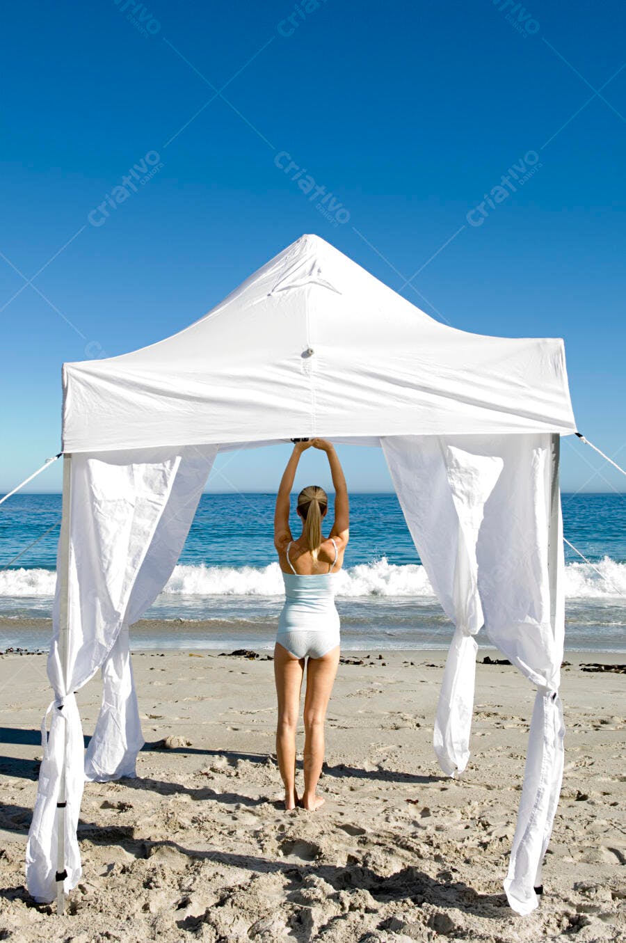 Mulher na praia sob gazebo branco