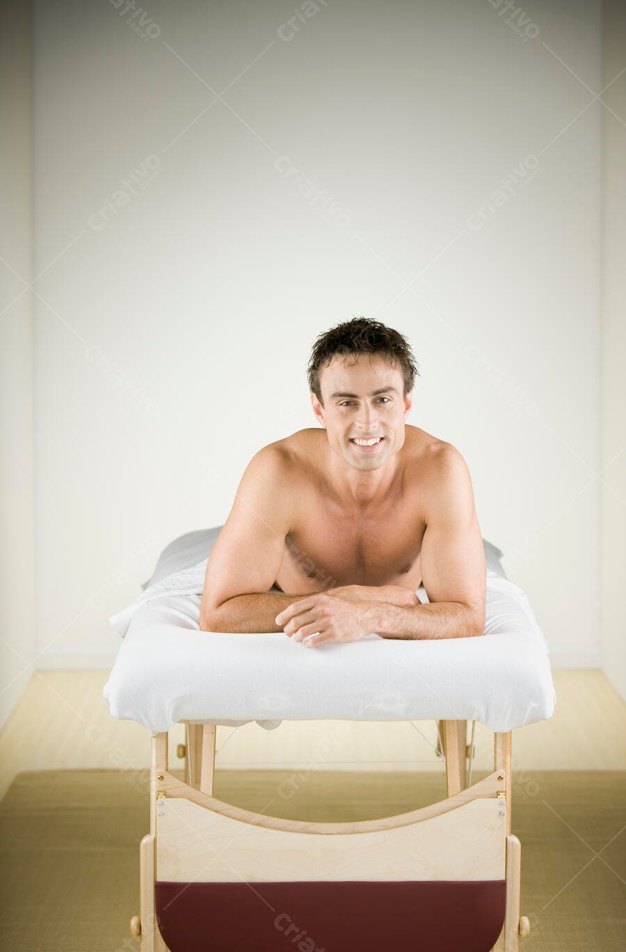 Homem sorrindo numa mesa de massagem