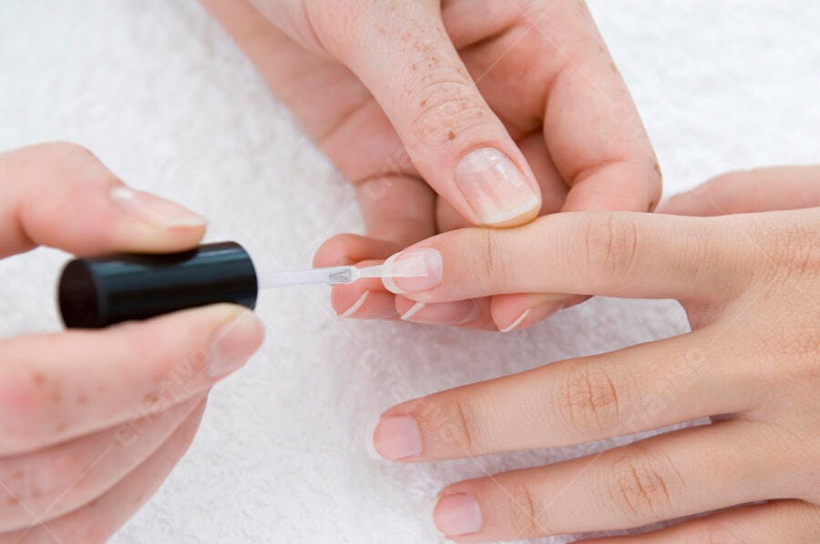 Unhas sendo pintadas com esmalte incolor