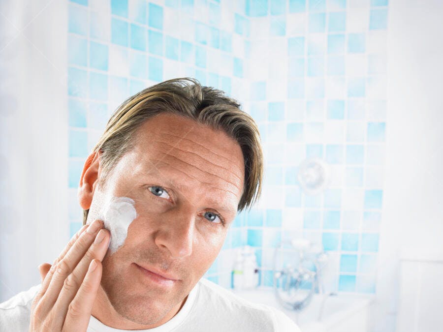 Homem aplicando creme facial no banheiro
