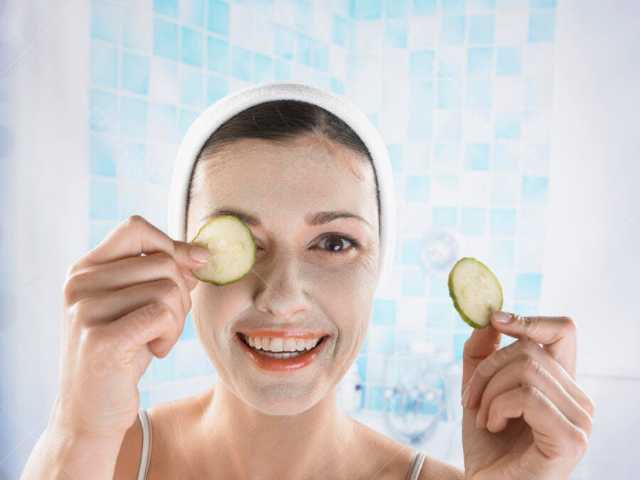 Mulher feliz com máscara facial e pepino