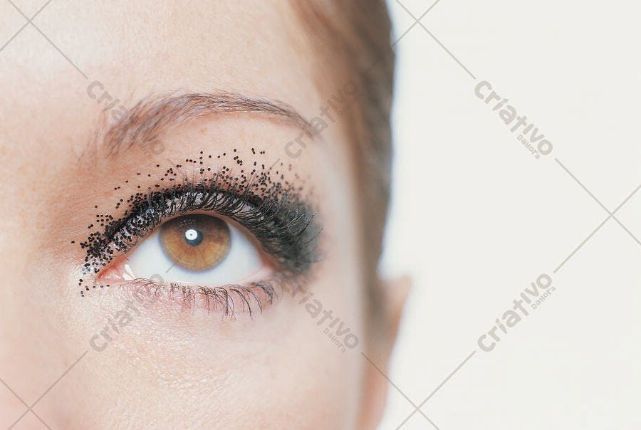 Olho feminino com maquiagem escura e glitter
