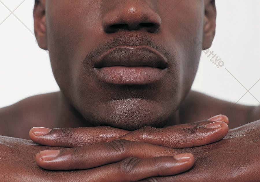 Rosto de homem negro com mãos entrelaçadas
